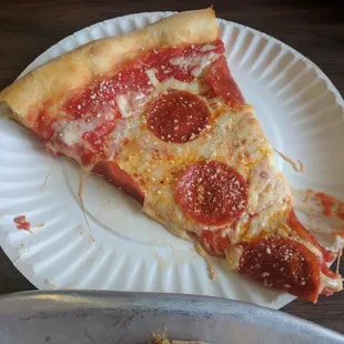 a slice of pepperoni pizza on a paper plate