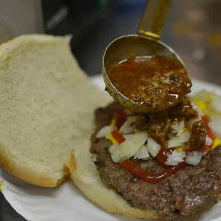 a hamburger being drizzled with sauce