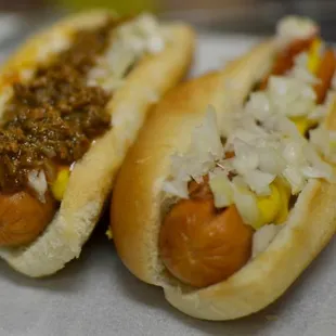 two hotdogs with mustard and onions