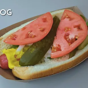 a hot dog with pickles and tomatoes