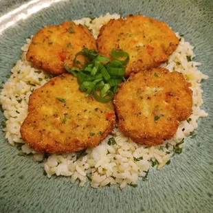 three fried fish cakes on a bed of rice