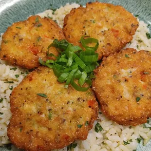 four fried fish cakes on a bed of rice