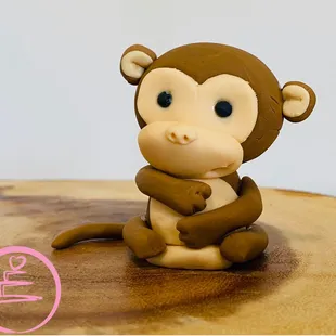 a clay monkey sitting on a wooden table