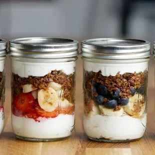 four jars of yogurt with fruit and granola