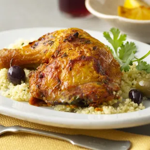 a plate of chicken with rice and olives