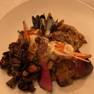 Wagyu top with a prawn, scallop, and sided by mussels, roasted veggies, mashed potatoes, and a mushroom reduction.