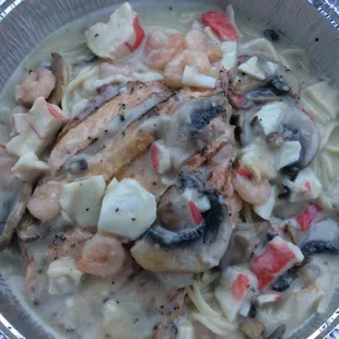 a bowl of pasta with shrimp, mushrooms, and tomatoes