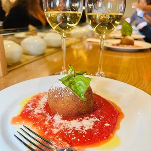 a close up of a plate of food and two glasses of wine