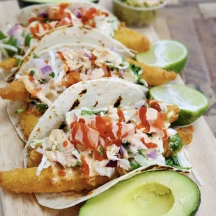 Our fish tacos (wild-caught) are served on a warm bed of flour tortillas, topped with  cabbage, cilantro, lime, queso crumble, sriracha