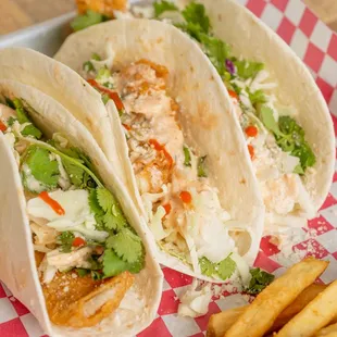 Our fish tacos (wild-caught) are served on a warm bed of flour tortillas, topped with  cabbage, cilantro, lime, queso crumble, sriracha
