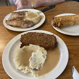 Pork chops and meatloaf with deep fried corn, mashed potatoes and gravy.