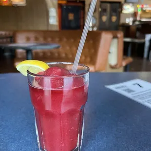 a red drink with a lemon wedge