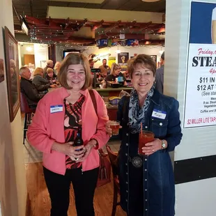 two women standing in front of a poster