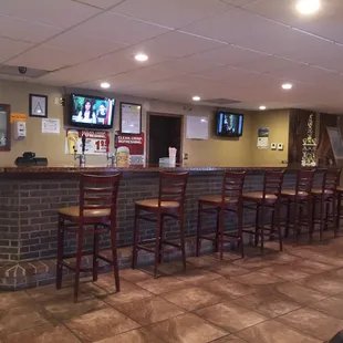 a bar with stools and televisions