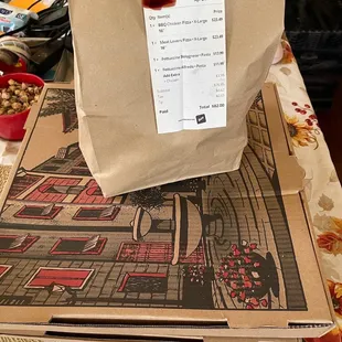 a paper bag on top of a pizza box