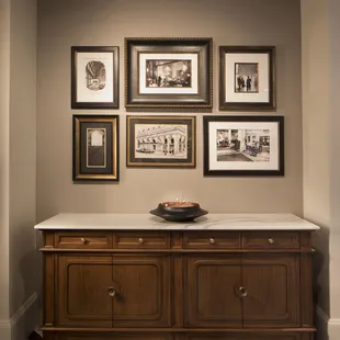a wall of framed photographs and a bowl on a marble countertop
