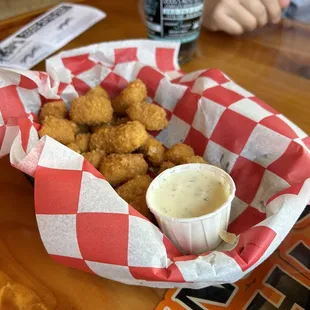 a basket of fried tater tots and a cup of sauce
