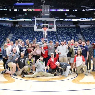 a group of people posing for a picture in front of a basketball court