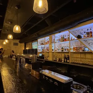 a dimly lit bar with people sitting at the bar