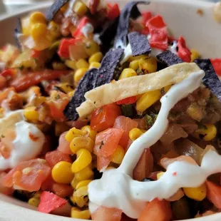 Bowl with cauliflower rice, dark meat chicken, extra roasted corn and peppers topped with sour cream and tortilla strips