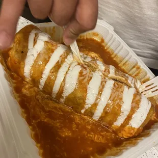 a person eating a burrito in a styrofoam container