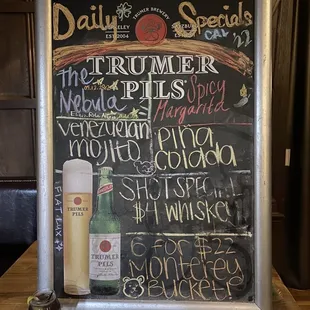 a chalk board with a menu and a glass of wine