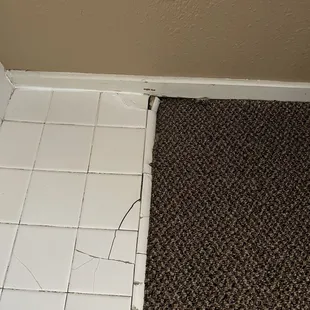 Broken tiles next to bathtub inside the bedroom