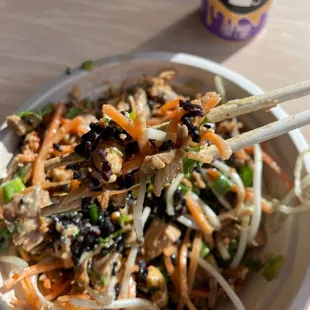 a bowl of asian food with chopsticks