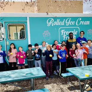  a group of children posing in front of a food truck