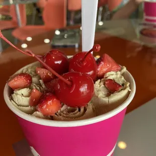 a cup of ice cream with cherries on top