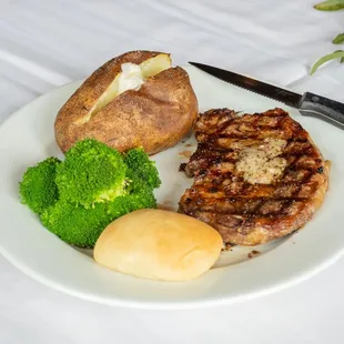 a plate of meat, broccoli, and a baked potato