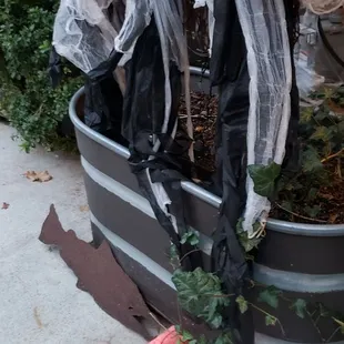 three creepy dolls in a barrel planter