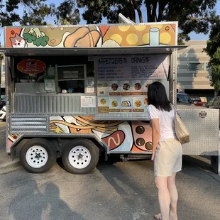 a woman standing in front of a food truck