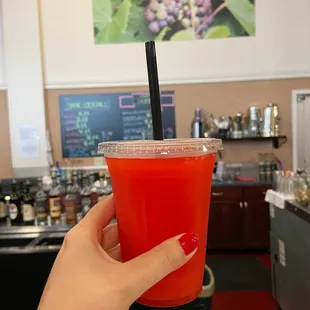 a hand holding a red drink