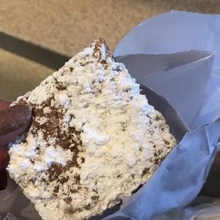 a hand holding a piece of cake