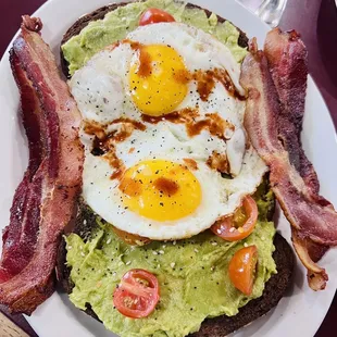 Avocado Toast with sunny side up eggs and a side of bacon