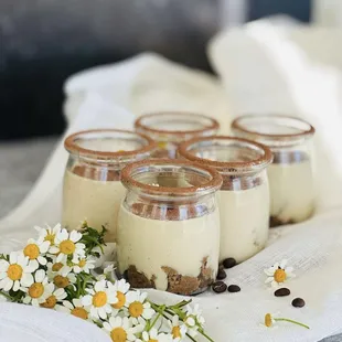 four small jars of dessert on a table