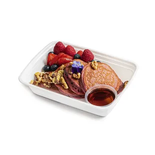 a plate of pancakes, berries, and syrup