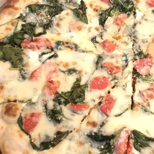 a pizza with spinach, tomatoes, and cheese