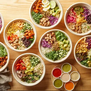 a variety of bowls of food on a wooden table