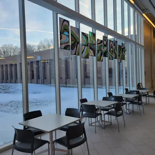 tables and chairs in front of a large window
