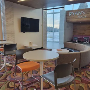 a room with chairs, tables, and a flat screen tv