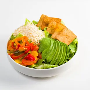 a bowl of salad with tofu, avocado, and bread