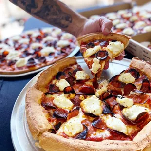 a person taking a slice of pizza