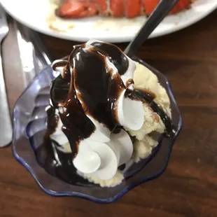 a bowl of ice cream with chocolate sauce and strawberries