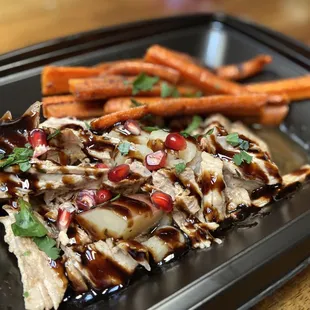 chicken and carrots on a black plate