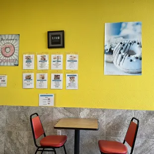 a table and two chairs in front of a yellow wall