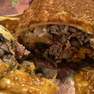 Smothered burrito close up: added onions and peppers, protein is steak.