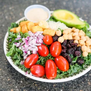 a bowl of salad with cherry tomatoes, chickpeas, avocado, and lettuce