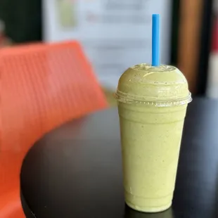 a smoothie in a plastic cup with a blue straw